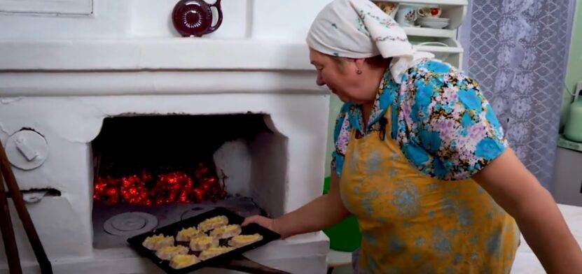 Женщина ставит в печь калитки